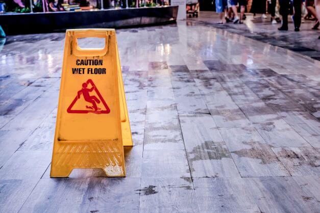 A wet floor with a yellow sign indicating "CAUTION WET FLOOR"